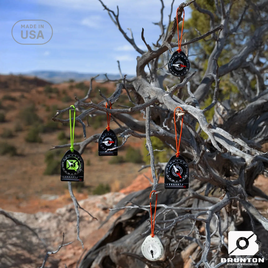 Brunton branded compasses hanging from a tree branch