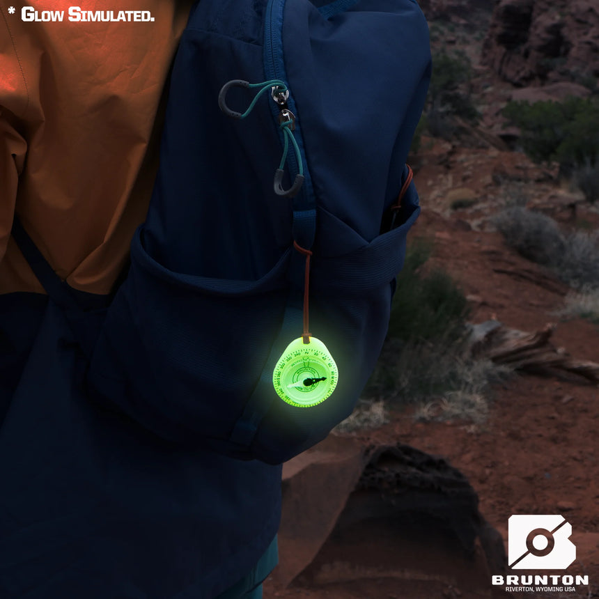 Glowing green light attached to a backpack in a desert setting
