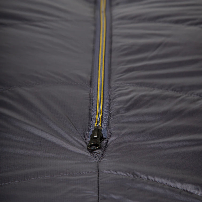 Mountain Equipment Helium GT 250 Sleeping Bag in Anvil Grey packed into waterproof roll-top stuff sack showing lightweight packable construction