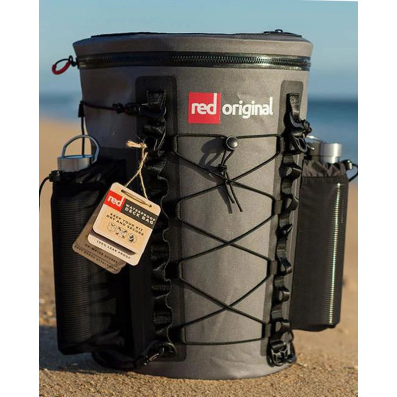 Red Paddle 22L Waterproof SUP Deck Bag - Sitting on Sand With Tag and Bottles In Side Pockets