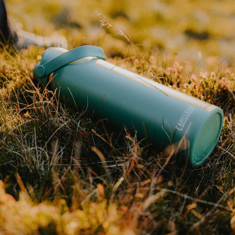 Camelbak Thrive™ Chug 25oz Bottle, Insulated Stainless Steel Outdoor Action- Product on Field