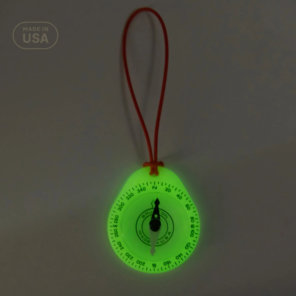 Glowing green compass with a red string on a dark background
