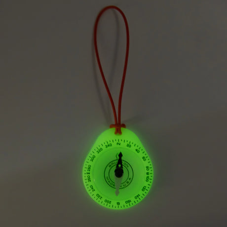 Glowing green compass with a red string on a dark background