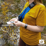 Person in yellow shirt using a Brunton compass in a natural setting